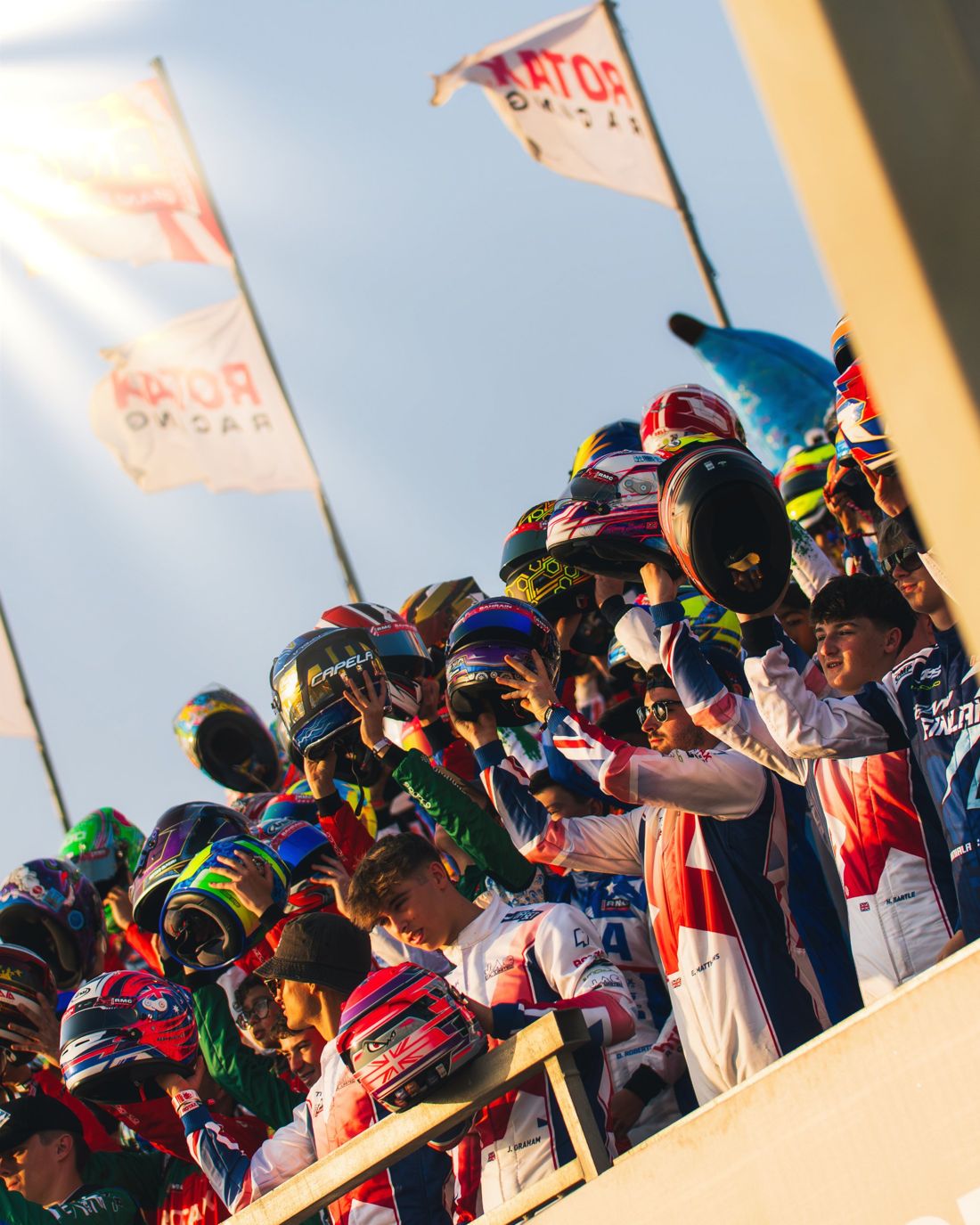 Drivers raise their helmets in the grandstand