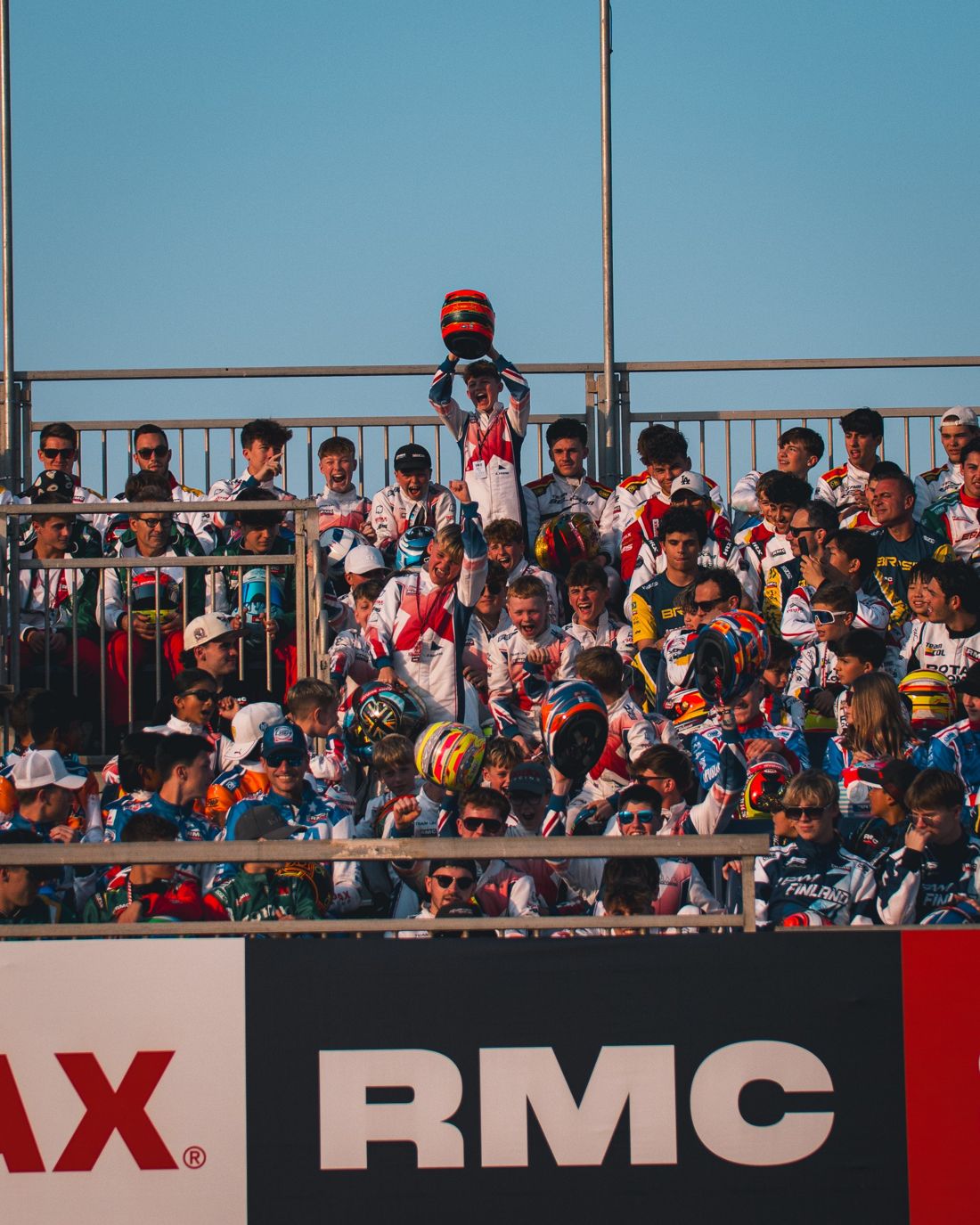 Drivers cheer in the grandstand above the RMC banner