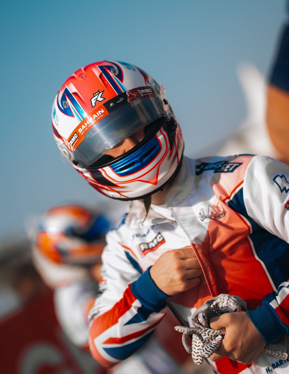 Driver in Bahrain-stickered helmet zips up his suit