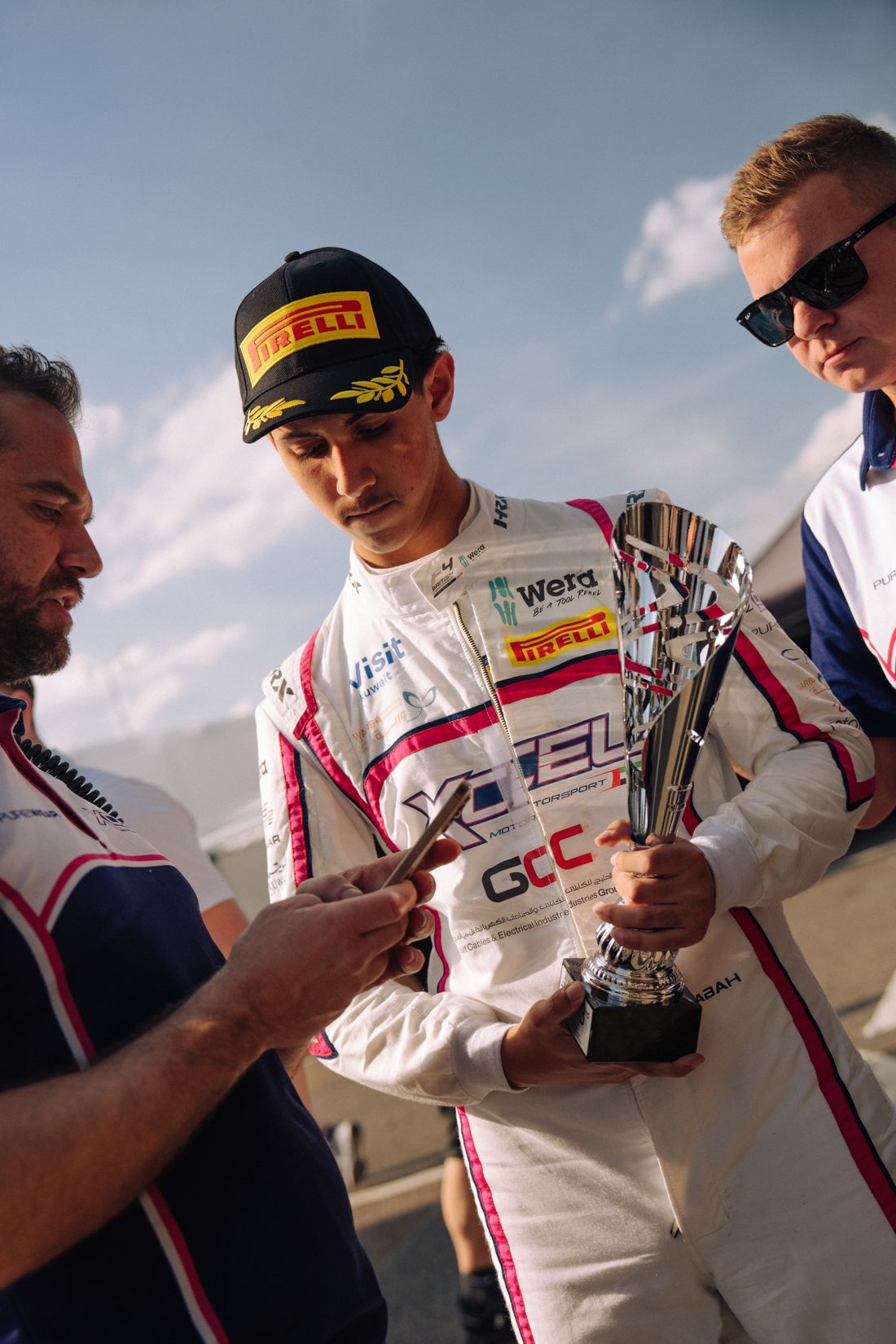 Race winner checks his phone holding the trophy