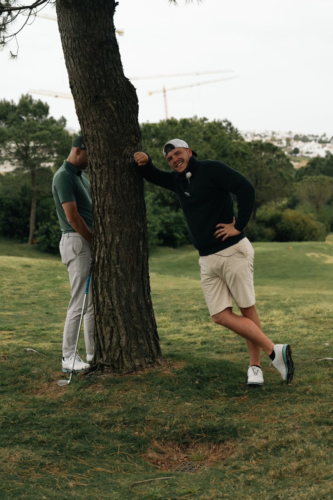 Golfer poses against a tree