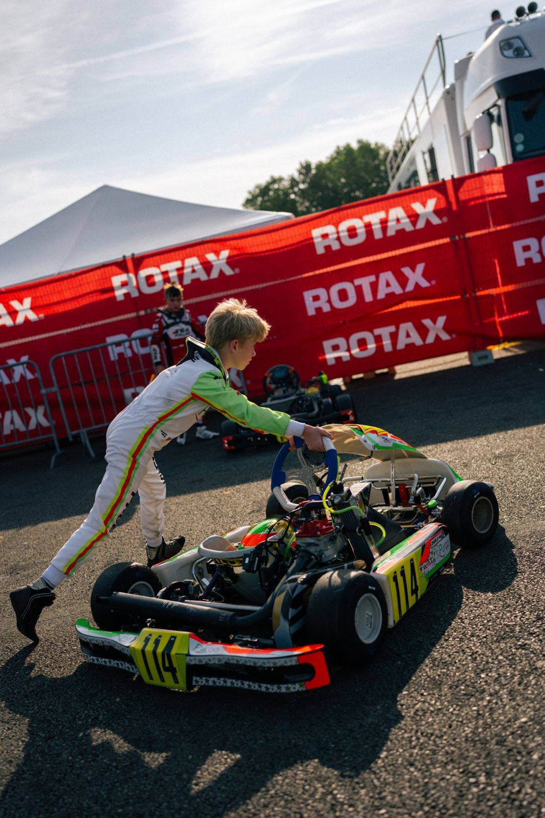 Charlie Page pushes his kart past Rotax banners